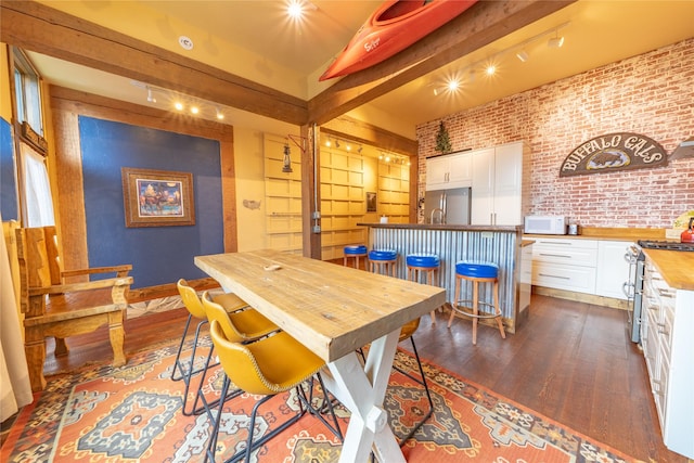 439 Osborn Ave Unit 115, Bigfork, MT 59911 - dining room with dark wood-type flooring, brick wall, rail lighting, and beamed ceiling