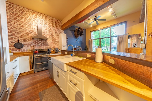 439 Osborn Ave Unit 115, Bigfork, MT 59911 - kitchen featuring double oven range, wooden counters, wall chimney range hood, a ceiling fan, and brick wall