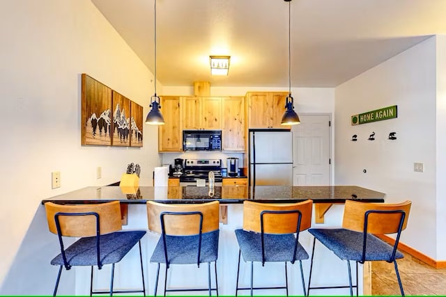 3832 Tamarack Ave Unit 2B, Whitefish, MT 59937 - kitchen with stainless steel appliances, a peninsula, a breakfast bar, and light brown cabinets