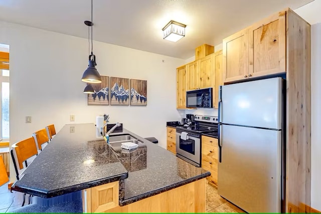 3832 Tamarack Ave Unit 2B, Whitefish, MT 59937 - kitchen featuring appliances with stainless steel finishes, light brown cabinets, a peninsula, and a breakfast bar area