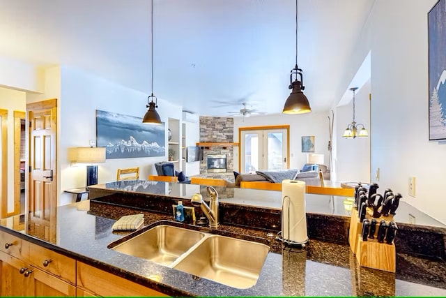 3832 Tamarack Ave Unit 2B, Whitefish, MT 59937 - kitchen with a ceiling fan, dark stone counters, hanging light fixtures, and a fireplace