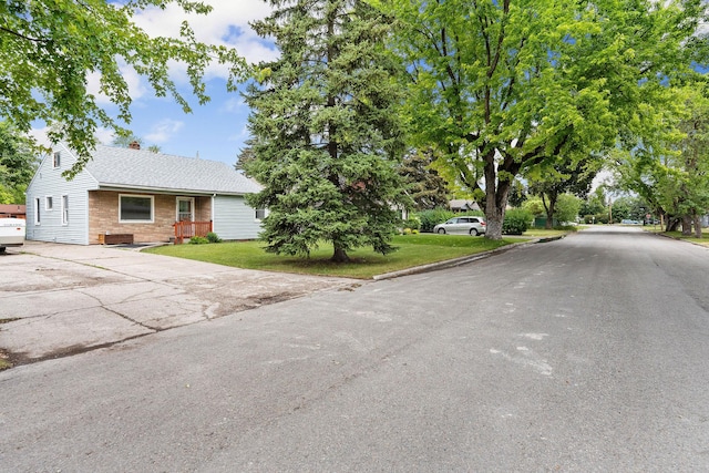 1307 4th St W, Kalispell, MT 59901 - view of front of house with driveway, a front lawn, brick siding, roof with shingles, and a chimney