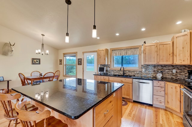 109 Como Vista Ln, Hamilton, MT 59840 - kitchen featuring stainless steel dishwasher, light brown cabinets, a breakfast bar, lofted ceiling, and backsplash