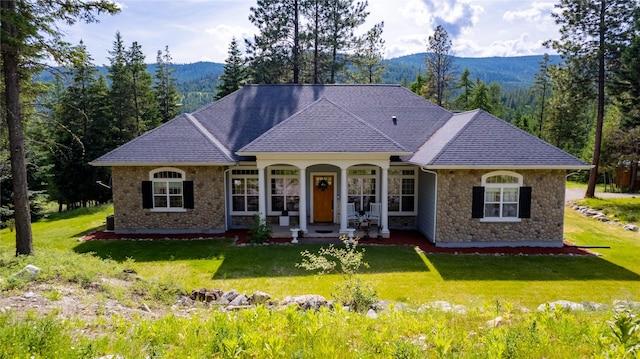 20245 Swan View Rd, Rollins, MT 59931 - view of front facade with stone siding, a porch, a mountain view, and a front lawn