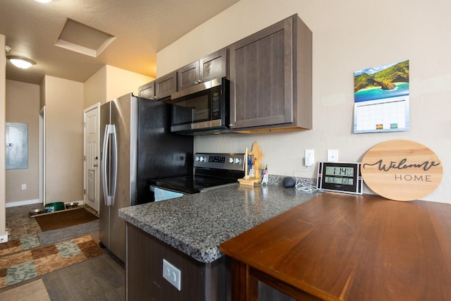 618 W Adams St, Three Forks, MT 59752 - kitchen with stainless steel appliances, dark brown cabinetry, dark countertops, a peninsula, and dark wood-type flooring