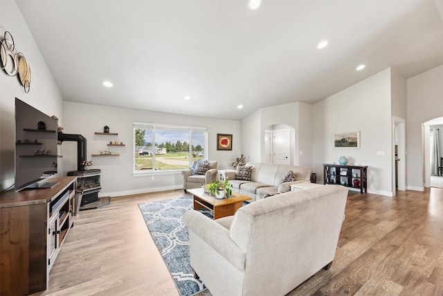 4460 Sunburst Ln, Stevensville, MT 59870 - living area featuring arched walkways, a wood stove, light wood finished floors, recessed lighting, and vaulted ceiling