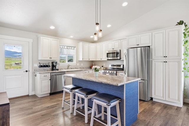 4460 Sunburst Ln, Stevensville, MT 59870 - kitchen with stainless steel appliances, a breakfast bar area, white cabinets, recessed lighting, and wood finished floors