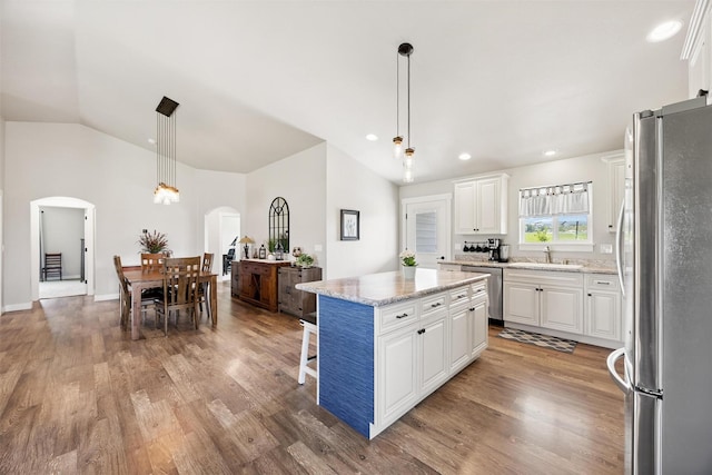 4460 Sunburst Ln, Stevensville, MT 59870 - kitchen featuring stainless steel appliances, arched walkways, white cabinetry, wood finished floors, and vaulted ceiling