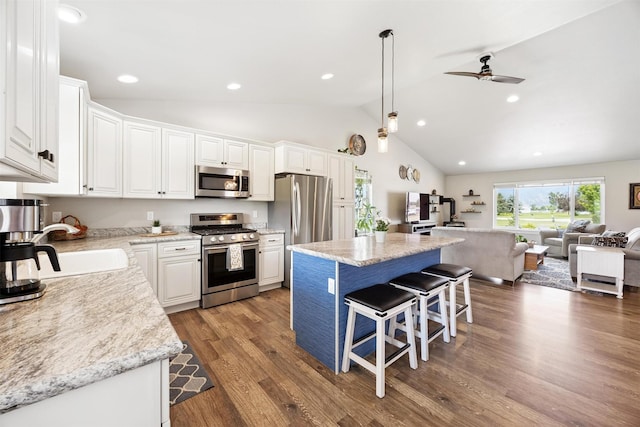 4460 Sunburst Ln, Stevensville, MT 59870 - kitchen featuring stainless steel appliances, open floor plan, white cabinets, a kitchen island, and a breakfast bar area