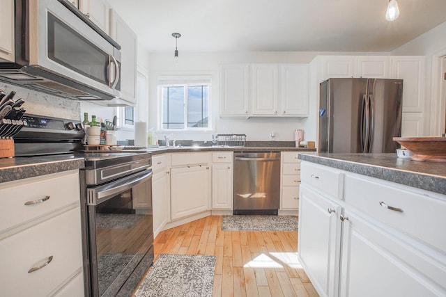 205 Kolczak Ln, Townsend, MT 59644 - kitchen featuring appliances with stainless steel finishes, dark countertops, light wood-style flooring, white cabinetry, and pendant lighting