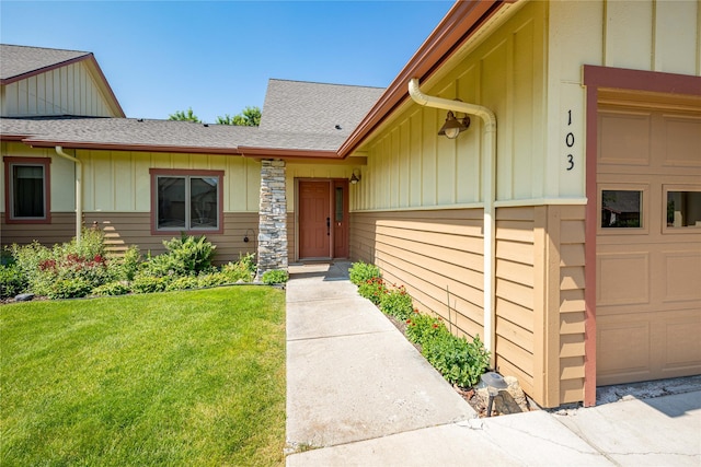 103 Crescent Lndg, Polson, MT 59860 - view of exterior entry featuring board and batten siding, a yard, roof with shingles, and an attached garage