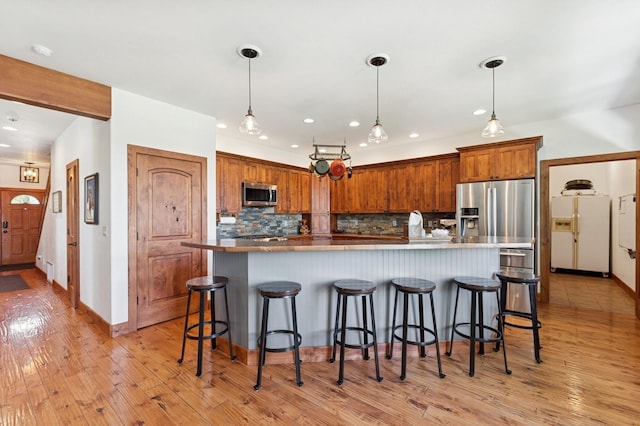 101 Heavens Peak Dr, Kalispell, MT 59901 - kitchen with stainless steel appliances, decorative backsplash, a kitchen breakfast bar, light wood-type flooring, and recessed lighting