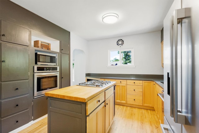 546 Woodworth Ave, Missoula, MT 59801 - kitchen with stainless steel appliances, light wood-style floors, butcher block countertops, arched walkways, and light brown cabinets
