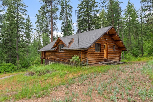 581 Timber Trl, Stevensville, MT 59870 - view of home's exterior with log exterior, a shingled roof, and a wooded view