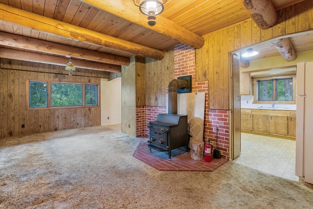 581 Timber Trl, Stevensville, MT 59870 - unfurnished living room with wood walls, a wood ceiling with exposed beams, plenty of natural light, a wood stove, and carpet