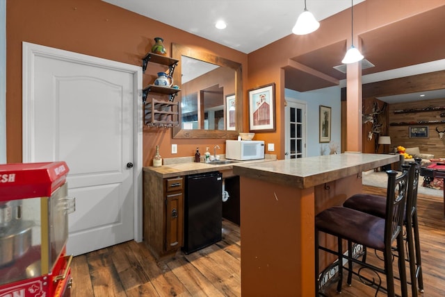 451 Creston Hatchery Rd, Kalispell, MT 59901 - kitchen featuring fridge, a breakfast bar area, white microwave, wood finished floors, and pendant lighting