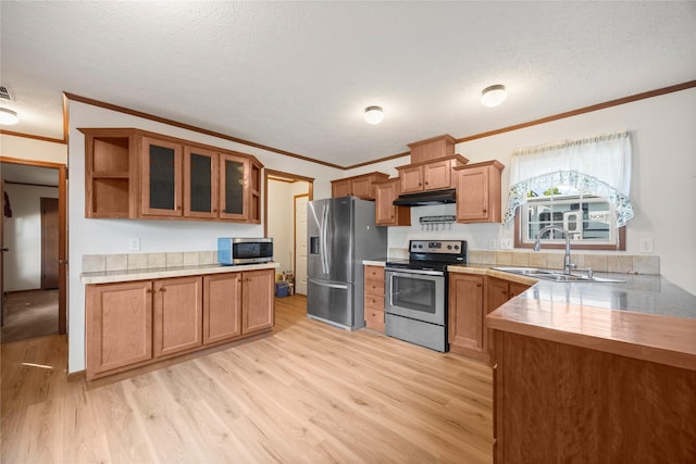 1100 E Oregon St Unit 13, Kalispell, MT 59901 - kitchen with appliances with stainless steel finishes, crown molding, under cabinet range hood, light wood-type flooring, and brown cabinetry