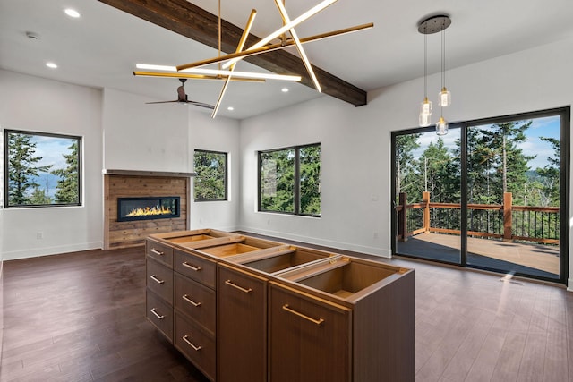 211 Whisper Ridge Dr, Bigfork, MT 59911 - kitchen featuring healthy amount of natural light, beam ceiling, dark wood finished floors, a glass covered fireplace, and hanging light fixtures