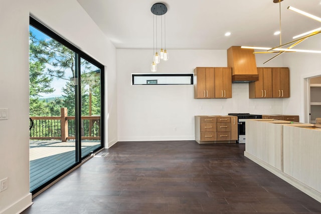 211 Whisper Ridge Dr, Bigfork, MT 59911 - kitchen with stainless steel gas stove, custom range hood, brown cabinets, hanging light fixtures, and dark wood finished floors
