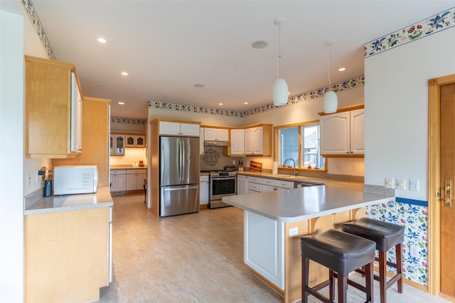 286 Arbour Dr W, Kalispell, MT 59901 - kitchen featuring appliances with stainless steel finishes, a peninsula, light countertops, a kitchen breakfast bar, and recessed lighting
