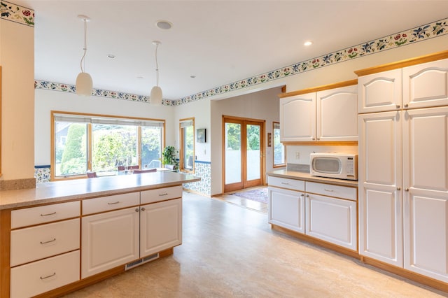 286 Arbour Dr W, Kalispell, MT 59901 - kitchen with white microwave, light countertops, healthy amount of natural light, recessed lighting, and white cabinets