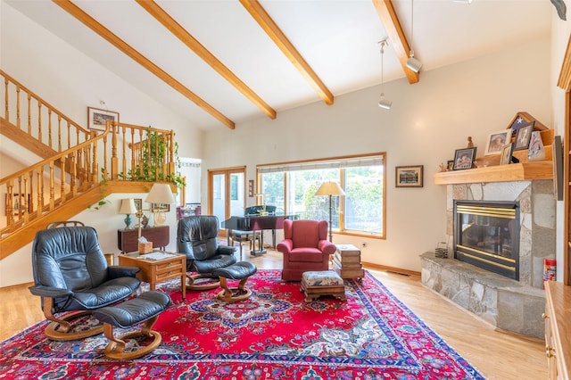 286 Arbour Dr W, Kalispell, MT 59901 - living area featuring wood finished floors, high vaulted ceiling, beam ceiling, a glass covered fireplace, and stairway