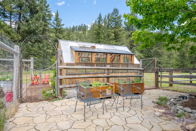 9995 Obrien Creek Rd, Missoula, MT 59804 - view of patio / terrace with a greenhouse, an outbuilding, and a gate