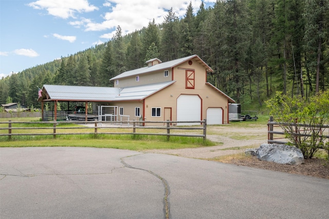 9995 Obrien Creek Rd, Missoula, MT 59804 - view of front of property featuring a wooded view, an outbuilding, driveway, a garage, and a metal roof