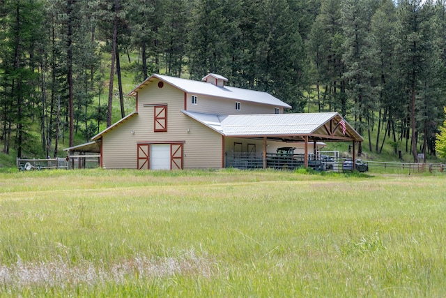 9995 Obrien Creek Rd, Missoula, MT 59804 - view of front of property with a barn, a view of trees, a detached garage, an outdoor structure, and a metal roof