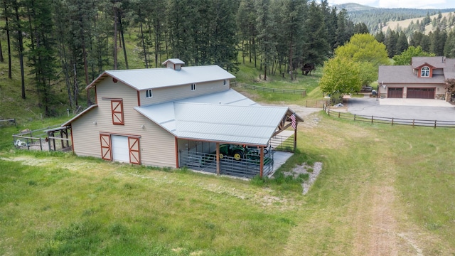 9995 Obrien Creek Rd, Missoula, MT 59804 - rear view of house with an outdoor structure, a barn, a view of trees, a garage, and an exterior structure