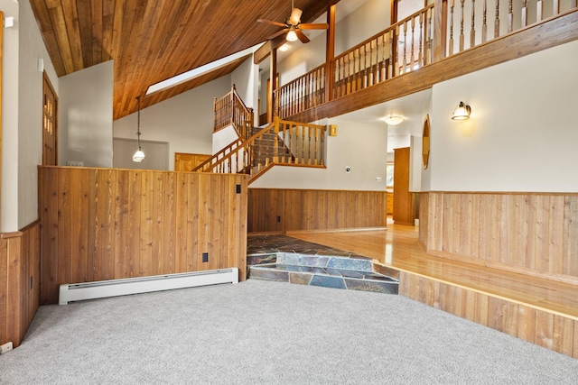 9995 Obrien Creek Rd, Missoula, MT 59804 - staircase featuring a baseboard radiator, wooden walls, carpet, wainscoting, and high vaulted ceiling