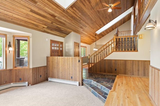 9995 Obrien Creek Rd, Missoula, MT 59804 - unfurnished living room with baseboard heating, a skylight, stairs, wainscoting, and wooden walls