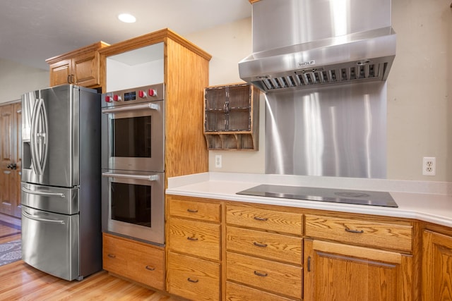 9995 Obrien Creek Rd, Missoula, MT 59804 - kitchen featuring stainless steel appliances, wall chimney exhaust hood, light wood-style flooring, light countertops, and brown cabinets