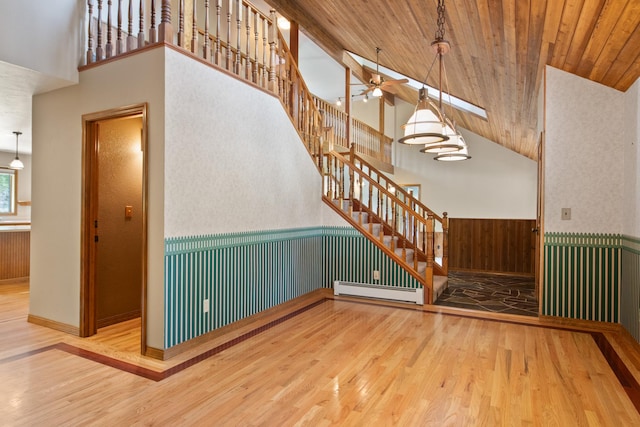9995 Obrien Creek Rd, Missoula, MT 59804 - unfurnished living room with baseboard heating, stairway, wood finished floors, wainscoting, and high vaulted ceiling