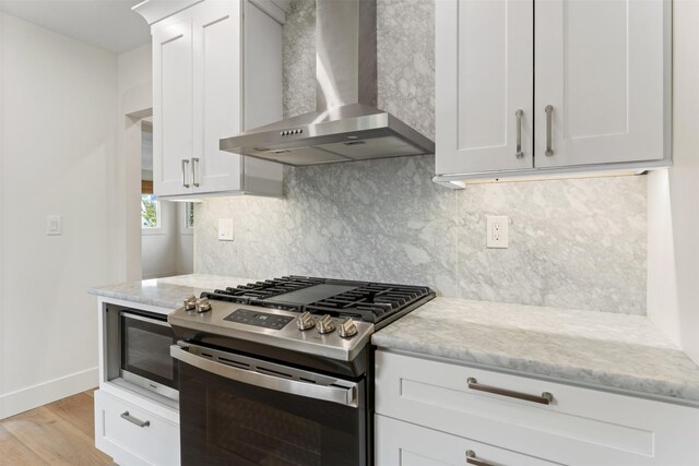 632 Stephens Ave, Missoula, MT 59801 - kitchen with stainless steel appliances, wall chimney exhaust hood, light stone counters, and white cabinetry