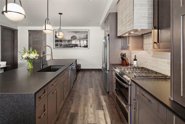 311E Akers Ln Unit E, Whitefish, MT 59937 - kitchen featuring stainless steel appliances, dark countertops, dark wood finished floors, a kitchen island with sink, and decorative backsplash