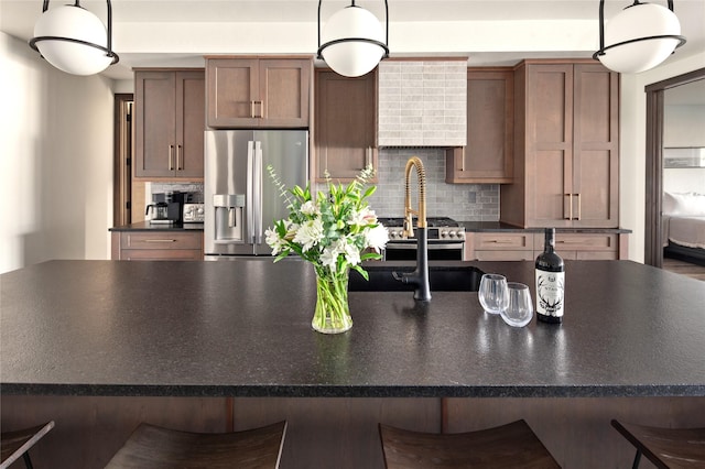 311E Akers Ln Unit E, Whitefish, MT 59937 - kitchen with stainless steel fridge with ice dispenser, dark countertops, tasteful backsplash, wall chimney exhaust hood, and a breakfast bar area