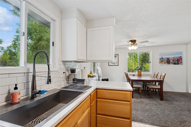 1970 Benchmark Ln, Whitefish, MT 59937 - kitchen featuring backsplash, a ceiling fan, white cabinetry, light countertops, and a peninsula