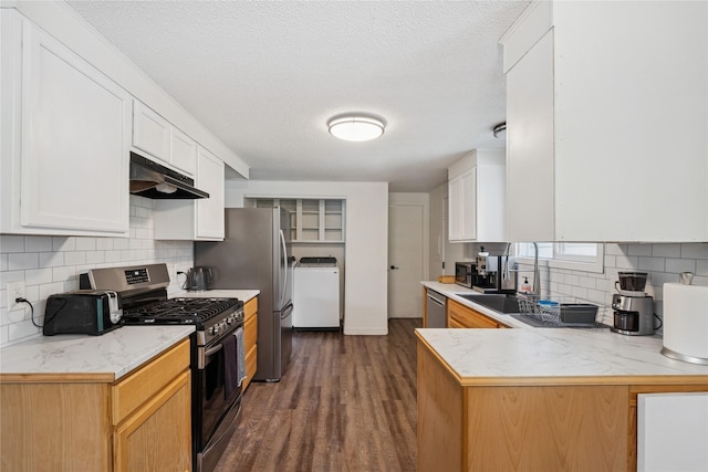 1970 Benchmark Ln, Whitefish, MT 59937 - kitchen with stainless steel appliances, under cabinet range hood, washer / clothes dryer, decorative backsplash, and dark wood finished floors