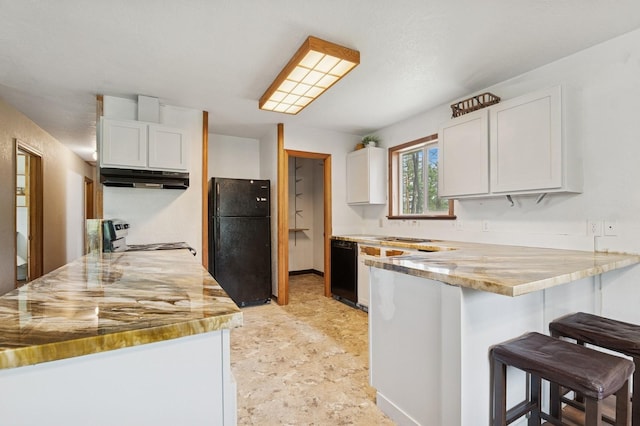257 Fawn Trl, Whitefish, MT 59937 - kitchen with black appliances, under cabinet range hood, a peninsula, a breakfast bar, and white cabinets