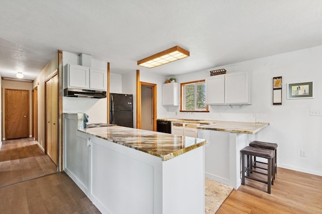 257 Fawn Trl, Whitefish, MT 59937 - kitchen featuring black appliances, a peninsula, under cabinet range hood, and white cabinetry