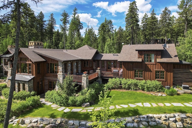 1263 Spencer Ridge Rd, Whitefish, MT 59937 - rear view of house with board and batten siding, stone siding, a shingled roof, and a deck