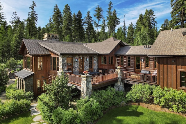 1263 Spencer Ridge Rd, Whitefish, MT 59937 - rear view of property with stone siding, board and batten siding, a wooden deck, and a shingled roof