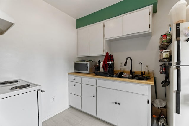 105 S Clifton St, Darby, MT 59829 - kitchen featuring stainless steel microwave, white electric range oven, light countertops, white cabinets, and ventilation hood