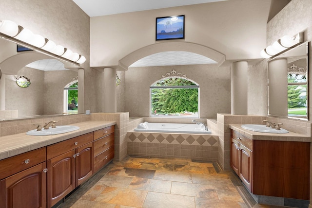 18 Buffalo Hill Cir, Kalispell, MT 59901 - bathroom featuring two vanities, a garden tub, stone tile floors, and decorative backsplash