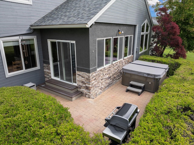 18 Buffalo Hill Cir, Kalispell, MT 59901 - rear view of house featuring a hot tub, a patio, a shingled roof, entry steps, and stone siding