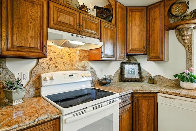 12 Pathfinder Trl, Bozeman, MT 59718 - kitchen with white appliances, under cabinet range hood, brown cabinetry, and light stone counters