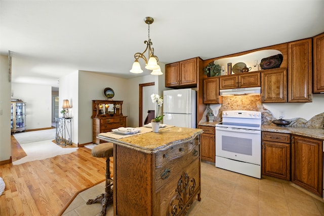 12 Pathfinder Trl, Bozeman, MT 59718 - kitchen featuring white appliances, under cabinet range hood, brown cabinets, a kitchen island, and a chandelier