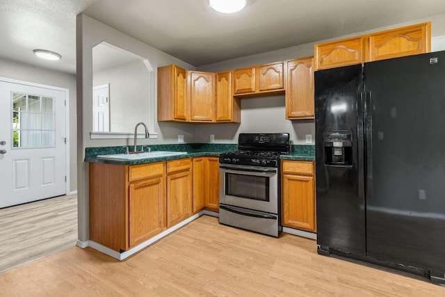620 N 4th St, Hamilton, MT 59840 - kitchen featuring black fridge, stainless steel gas range oven, light wood-type flooring, and dark countertops