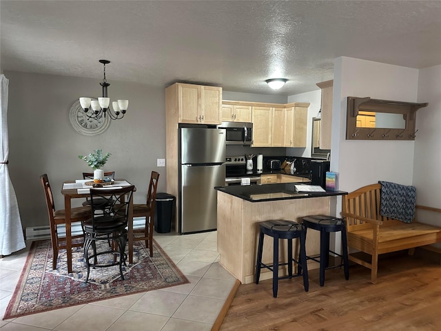 67 Crestwood Dr Unit A, Whitefish, MT 59937 - kitchen with appliances with stainless steel finishes, light brown cabinets, dark countertops, baseboard heating, and a peninsula